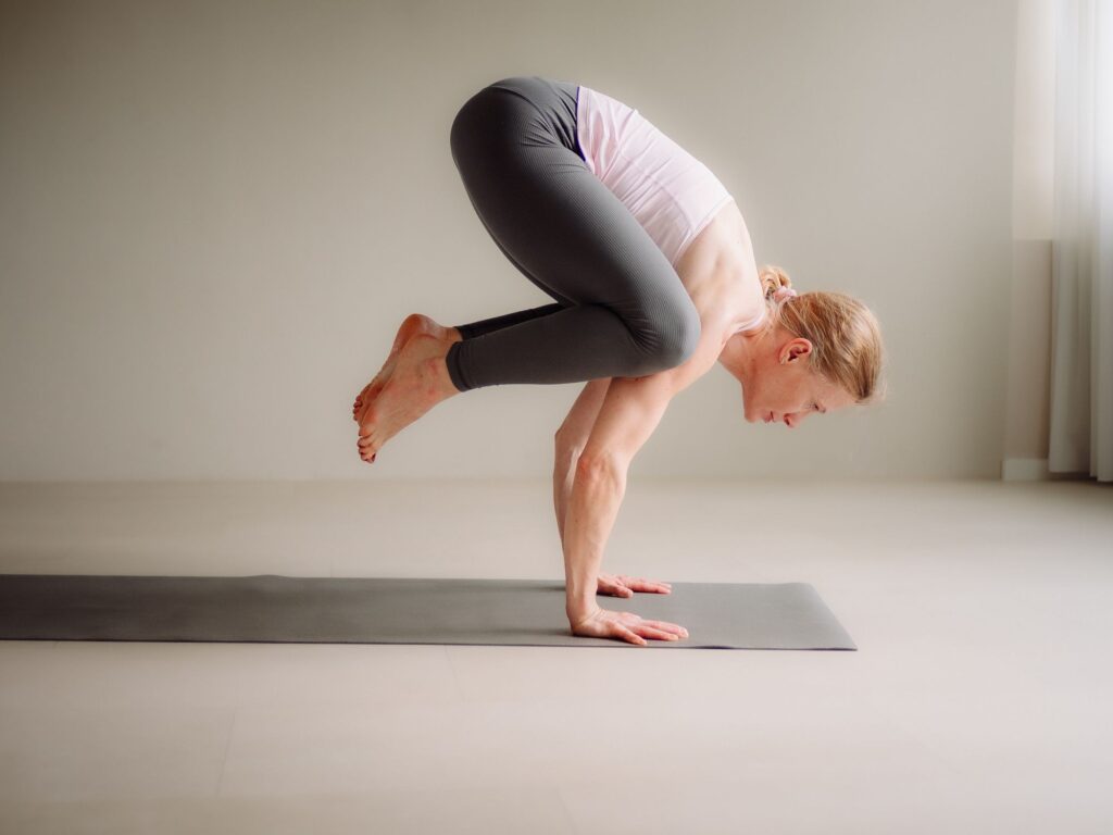 Yogalehrerin Ela Buchholz balanciert konzentriert in der Krähe auf den Händen